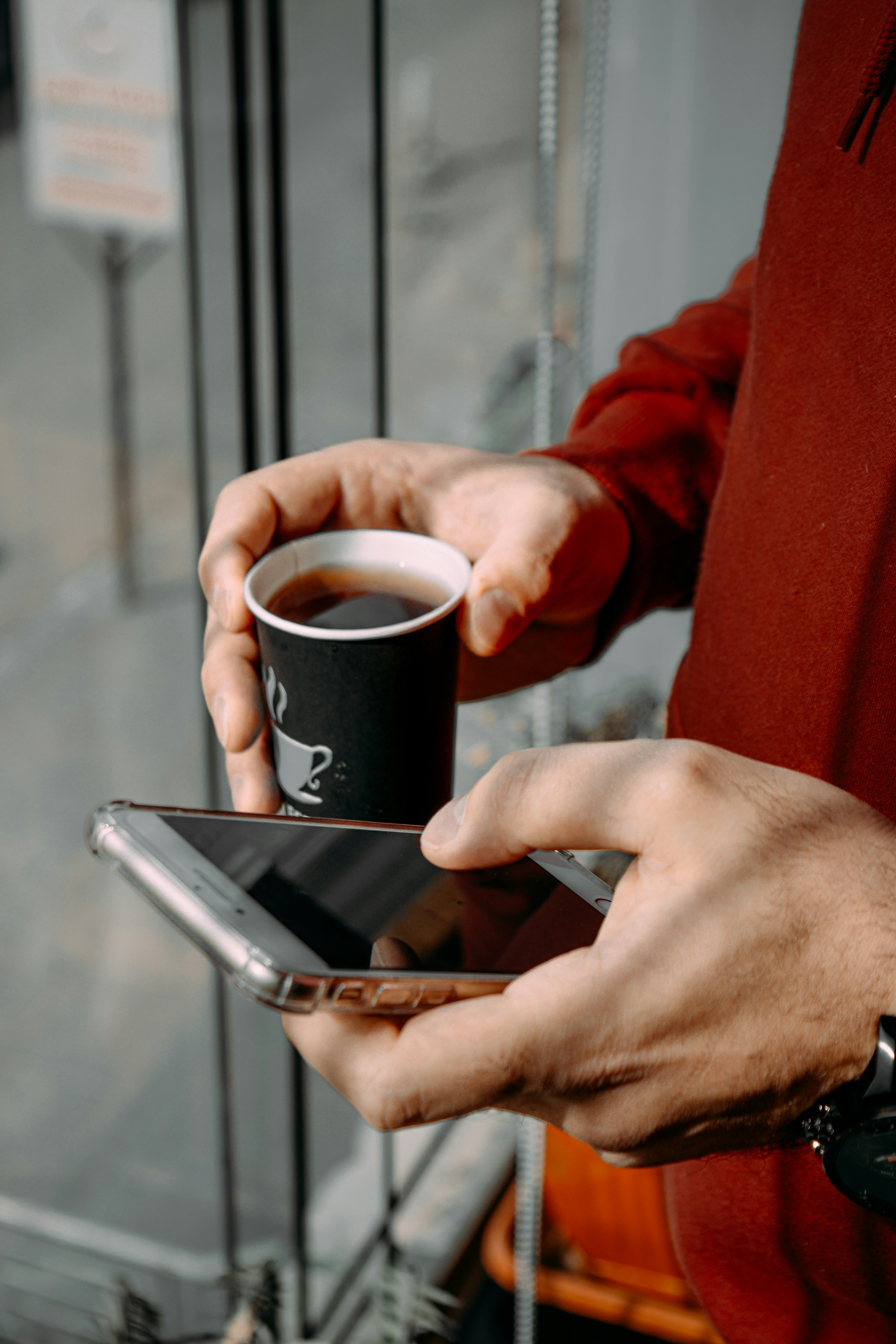 Vermieter prüft Bewerber-Anfragen am Smartphone mit Kaffee